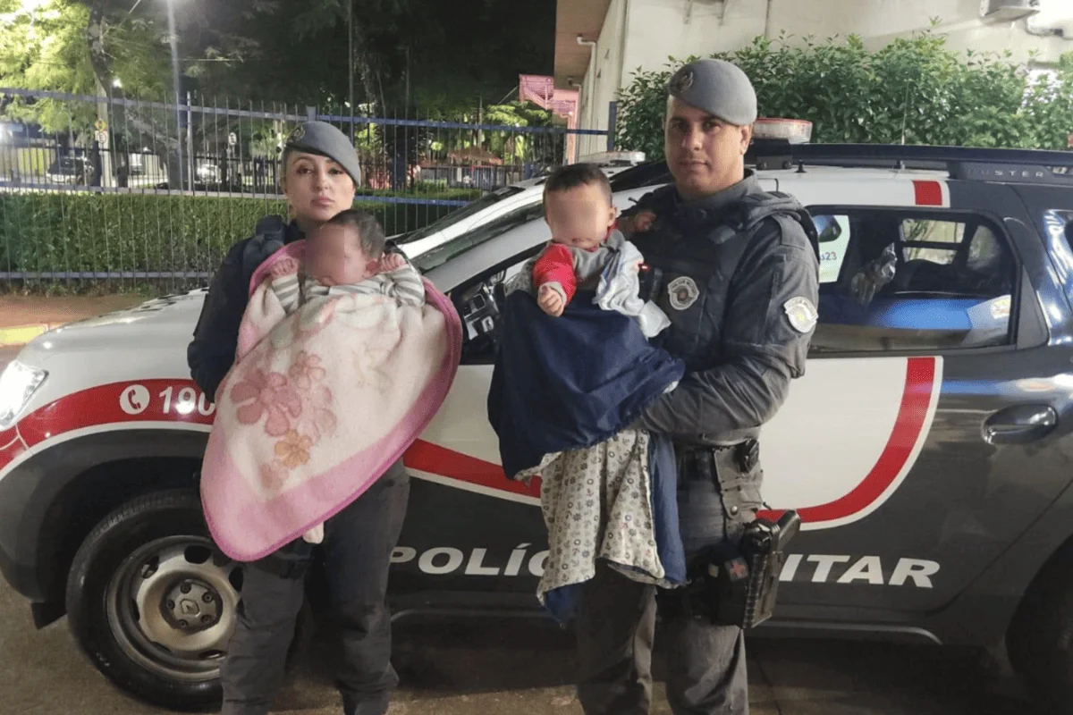 Imagem colorida de policiais militares com bebês resgatados abandonados em casa insalubre - Metrópoles